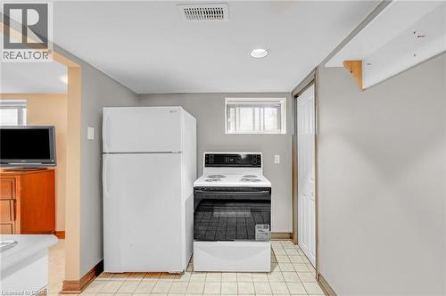 Kitchen area featuring a white top-freezer refrigerator, a white electric range, and a tiled floor - 1 Galbraith Drive, Hamilton, ON - Indoor