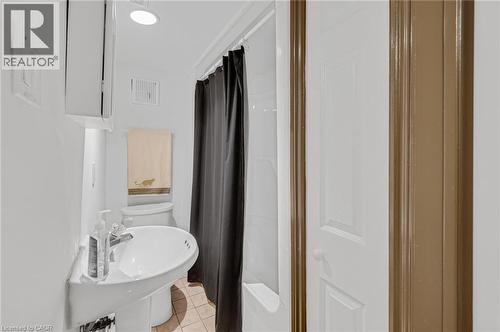 Bathroom featuring a pedestal sink, a toilet, and a shower-over-tub combination with a dark shower curtain - 1 Galbraith Drive, Hamilton, ON - Indoor Photo Showing Bathroom