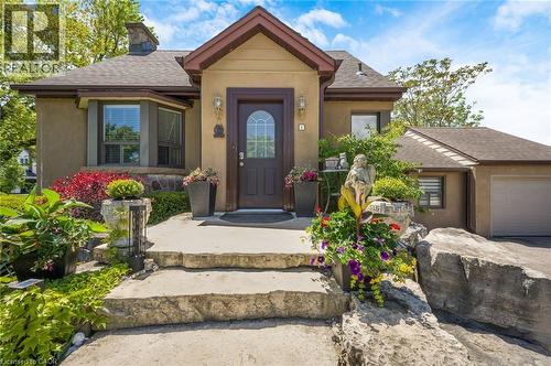 Stucco exterior with a peaked roofline, a bay window, and an attached single-car garage - 1 Galbraith Drive, Hamilton, ON - Outdoor With Facade