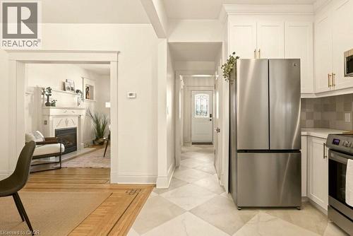 Kitchen featuring white shaker cabinetry with gold-tone hardware, stainless steel appliances, and a tiled backsplash - 106 Grosvenor Avenue N, Hamilton, ON - Indoor Photo Showing Kitchen