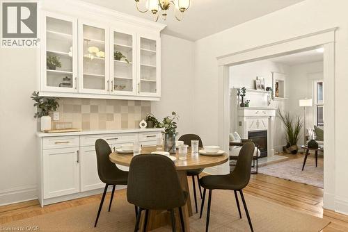 Dining area featuring wood-finish flooring and a built-in buffet with glass-front upper cabinetry - 106 Grosvenor Avenue N, Hamilton, ON - Indoor Photo Showing Dining Room