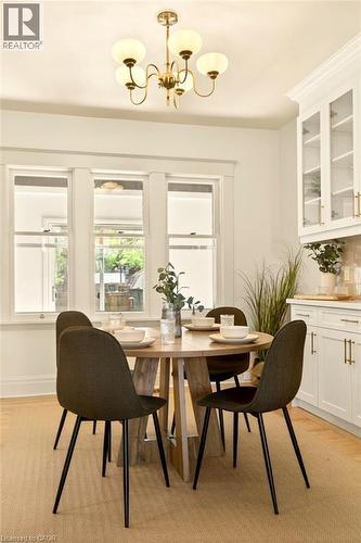 Bright dining area featuring a brass chandelier with frosted globes - 106 Grosvenor Avenue N, Hamilton, ON - Indoor Photo Showing Dining Room