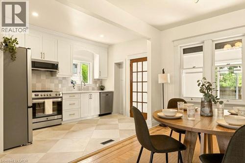 Kitchen featuring white cabinetry, stainless steel appliances, a tiled backsplash, and diamond-patterned floor tiles - 106 Grosvenor Avenue N, Hamilton, ON - Indoor Photo Showing Dining Room