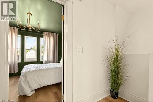 Room featuring a gold-toned chandelier, three pane windows, wood-finish flooring, and a neutral color palette - 106 Grosvenor Avenue N, Hamilton, ON - Indoor Photo Showing Bedroom
