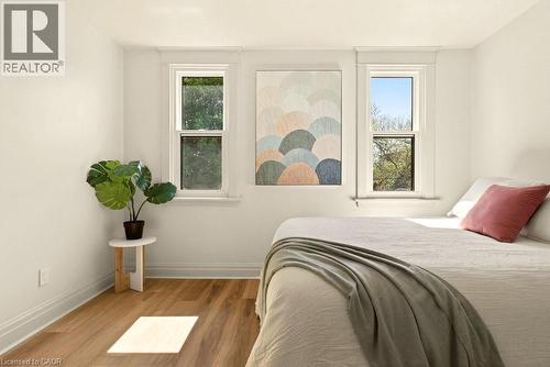 Bright interior space featuring two double-hung windows, light-toned walls, and wood-finish flooring - 106 Grosvenor Avenue N, Hamilton, ON - Indoor Photo Showing Bedroom