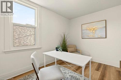 Bright interior space featuring a double-hung window with white trim, wood-finish flooring, white baseboards, and neutral wall paint - 106 Grosvenor Avenue N, Hamilton, ON - Indoor