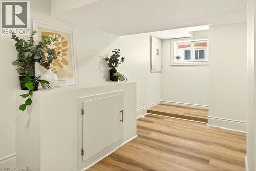Recessed wall storage featuring a built-in cabinet, wood-finish flooring, white baseboards, and a window providing natural illumination - 106 Grosvenor Avenue N, Hamilton, ON - Indoor Photo Showing Other Room