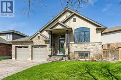 The property features a brick and stone facade, a peaked roofline, a two-car garage, and an arched window - 