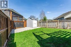 The property features a well-maintained lawn with a white storage shed - 