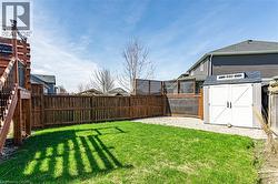 The property features a fenced backyard with a lawn area, a storage shed, and a wooden deck with stairs - 