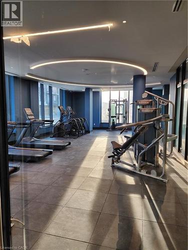 Fitness center with large format tile flooring, curved ceiling lighting, expansive windows, and a comprehensive selection of exercise equipment - 385 Winston Road Unit# 709, Grimsby, ON - Indoor Photo Showing Gym Room