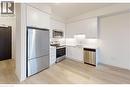 Featuring white shaker-style cabinetry, stainless steel appliances, white subway tile backsplash, and light wood-finish flooring - 385 Winston Road Unit# 709, Grimsby, ON  - Indoor Photo Showing Kitchen 
