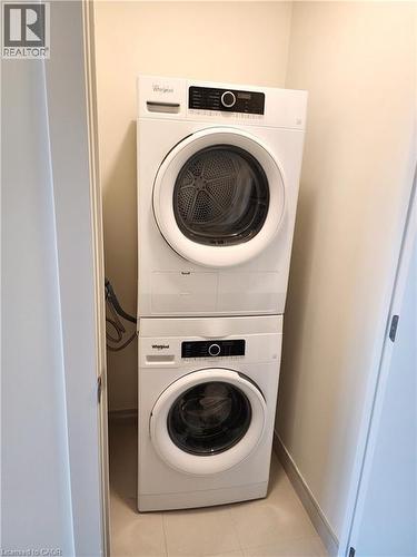 Stackable washer and dryer unit in a dedicated laundry alcove with tile flooring - 385 Winston Road Unit# 709, Grimsby, ON - Indoor Photo Showing Laundry Room