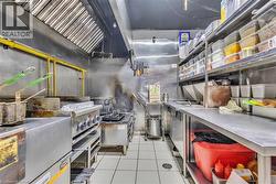Commercial-grade kitchen featuring stainless steel surfaces, integrated stovetop, and hood ventilation system - 