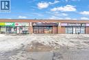 Commercial storefront featuring brick facade, multiple display windows, prominent signage, and a paved parking area - 402 King Street N, Waterloo, ON 