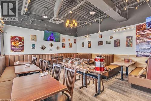 Spacious commercial interior featuring banquette seating, wood-finish flooring, and exposed ceiling ductwork - 402 King Street N, Waterloo, ON 