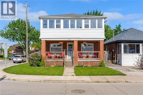 Brick and siding exterior featuring an enclosed upper-level porch with multiple windows - 121 Edgemont Street N, Hamilton, ON - Outdoor With Deck Patio Veranda With Facade
