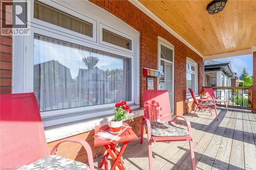 Inviting covered porch with a wood-finish ceiling, brick exterior, and wood-finish flooring - 121 Edgemont Street N, Hamilton, ON - Outdoor With Deck Patio Veranda