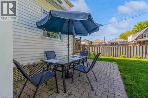 Paved patio area featuring interlocking brick, a perimeter fence, and a grassy yard - 121 Edgemont Street N, Hamilton, ON - Outdoor With Deck Patio Veranda With Exterior
