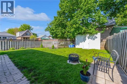Expansive backyard featuring a large grass lawn, a paved patio area, and a white storage shed - 121 Edgemont Street N, Hamilton, ON - Outdoor