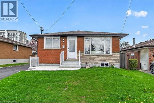 Brick facade home featuring a stone veneer accent, white trim windows, and a front entry door with a storm door - 74 Victor Boulevard, Hamilton, ON - Outdoor