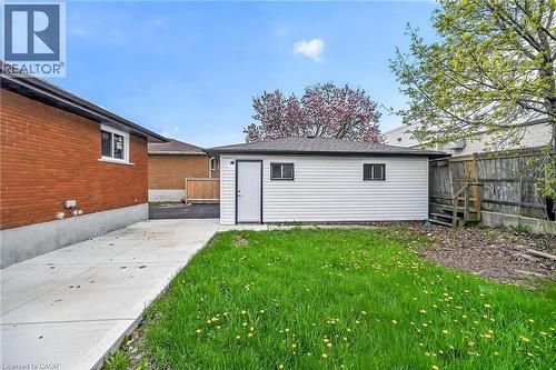 Detached auxiliary structure featuring white siding, a dark asphalt shingle roof, and a side entry door - 74 Victor Boulevard, Hamilton, ON - Outdoor With Exterior
