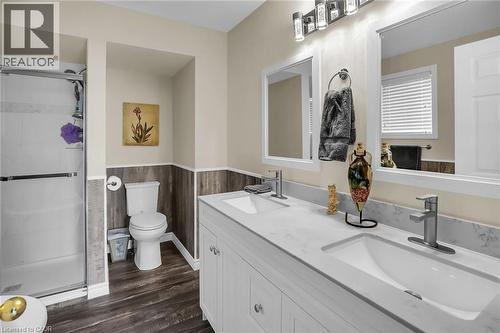 Bathroom featuring wainscoting, double vanity, a stall shower, and wood finished floors - 4432 Dennis Avenue, Beamsville, ON - Indoor Photo Showing Bathroom