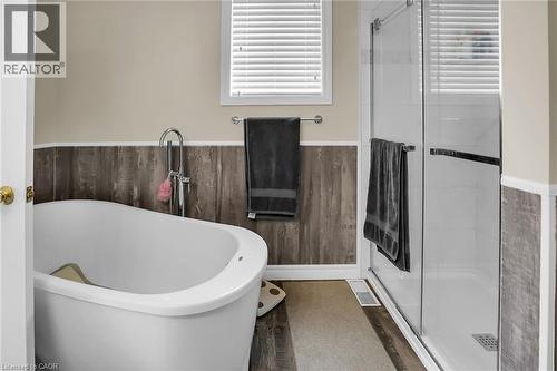 Full bath with a soaking tub, a shower shower, wainscoting, and wood finished floors - 4432 Dennis Avenue, Beamsville, ON - Indoor Photo Showing Bathroom