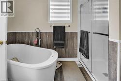Full bath with a soaking tub, a shower shower, wainscoting, and wood finished floors - 