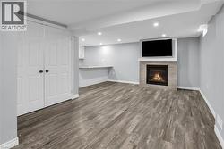 Finished basement with dark wood-type flooring, a fireplace, and recessed lighting - 