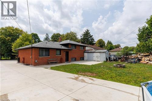 Brick exterior with dark-framed windows, a gray shingle roof, and a concrete patio - 18 Silverdale Crescent, London, ON - Outdoor