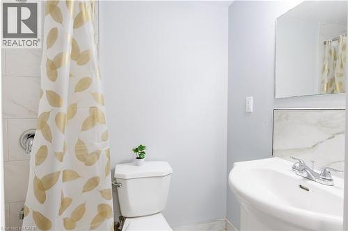 Full bathroom featuring a pedestal sink with chrome fixtures, a wall-mounted mirror, and white tiled shower surround - 18 Silverdale Crescent, London, ON - Indoor Photo Showing Bathroom