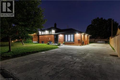 Brick exterior residence featuring a concrete driveway, established trees, a fenced side yard, and exterior lighting fixtures - 18 Silverdale Crescent, London, ON - Outdoor