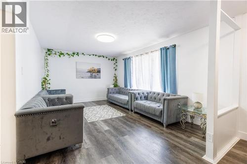Spacious living area featuring wood-finish flooring, white walls, and a large window with sheers - 18 Silverdale Crescent, London, ON - Indoor Photo Showing Living Room