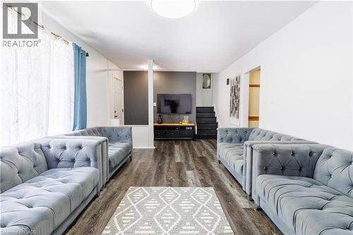 Spacious room featuring wood-finish flooring, a contemporary ceiling light fixture, and white walls - 18 Silverdale Crescent, London, ON - Indoor Photo Showing Living Room