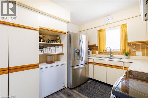 Kitchen featuring light-toned cabinetry with wood-finish accents, stainless steel refrigerator, and a double basin sink with a gooseneck faucet - 18 Silverdale Crescent, London, ON - Indoor Photo Showing Kitchen With Double Sink
