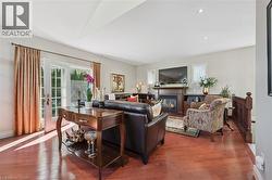 Spacious living area featuring rich wood-finish flooring, a fireplace with a wood mantel, and built-in shelving - 