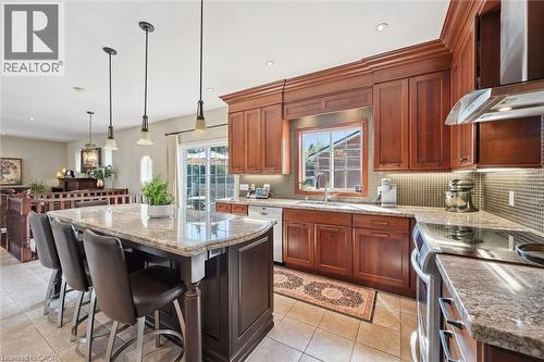Spacious kitchen featuring rich wood cabinetry, granite countertops, tile flooring, and a large central island with pendant lighting - 20 Bonniewood Drive, Drayton, ON - Indoor