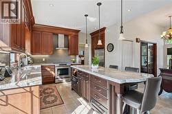 Gourmet kitchen featuring a large central island with seating, granite countertops, and rich wood cabinetry - 