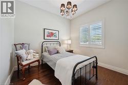 Neutral painted walls featuring dark wood-finish flooring, white window shutters, and a multi-arm chandelier with dark shades - 
