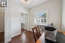 Room featuring wood-finish flooring, a window with louvered shutters, mirrored closet doors, and crown molding - 