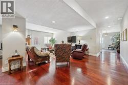 Spacious living area featuring rich wood-finish flooring, recessed lighting, and light-toned wall finishes - 