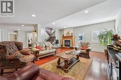 Spacious living area featuring wood-finish flooring, recessed lighting, and a fireplace with a wood mantle - 