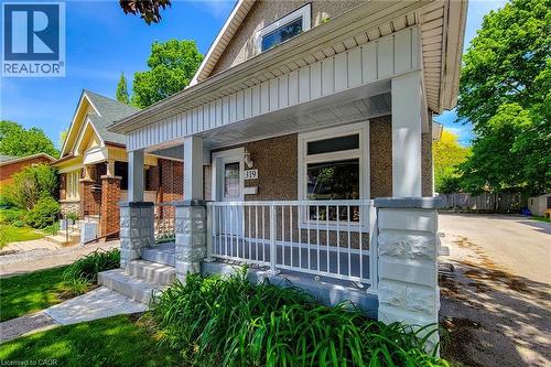 Inviting front porch featuring a white railing and stone-clad pillars - 319 King Street W, Dundas, ON - Outdoor With Deck Patio Veranda