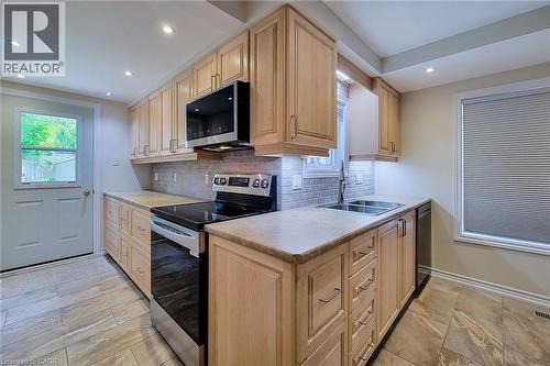 Kitchen featuring light wood cabinetry, stone-look tile flooring, and a stainless steel appliance suite - 319 King Street W, Dundas, ON - Indoor Photo Showing Kitchen With Double Sink