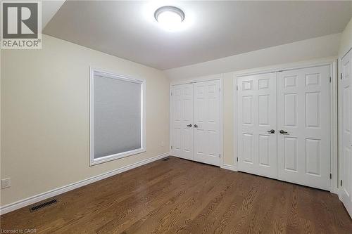 Bedroom featuring wood-finish flooring, a window with roller shade, two bi-fold closet doors, and recessed lighting - 319 King Street W, Dundas, ON - Indoor Photo Showing Other Room