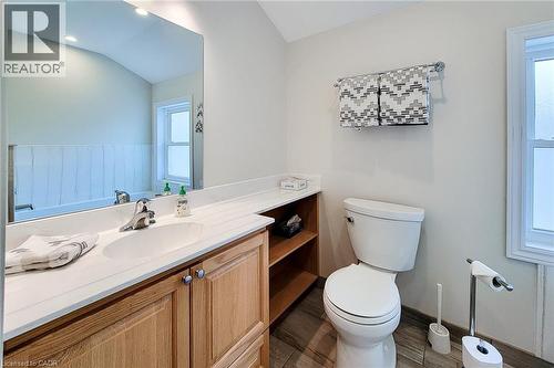 Bathroom featuring a wood-finish vanity with a white countertop and integrated sink, chrome faucet, and a large wall-mounted mirror - 319 King Street W, Dundas, ON - Indoor Photo Showing Bathroom