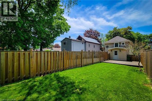 Expansive backyard featuring a manicured lawn, full privacy fencing, and a wooden deck - 319 King Street W, Dundas, ON - Outdoor