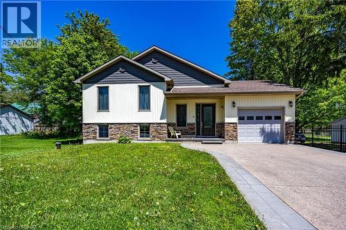 Modern home exterior featuring cream siding with dark gray shingle accents and a stone veneer foundation - 514 Fishers Glen Road, Vittoria, ON - Outdoor With Facade