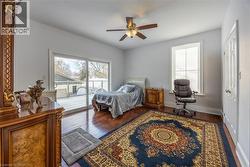 Bright interior space featuring wood-finish flooring, a ceiling fan with integrated lighting, and white walls - 